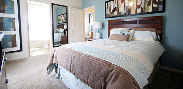 Interior of a bedroom at Harmony Oaks, with a double bed, bedstand and artwork hanging over the bed.